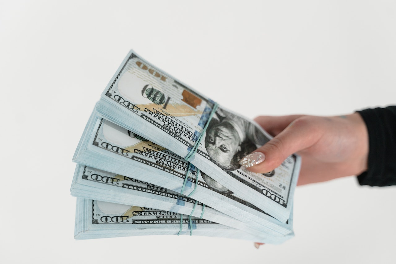 Close-Up-Shot-of-a-Person-Holding-Stack-of-Dollar-Bills