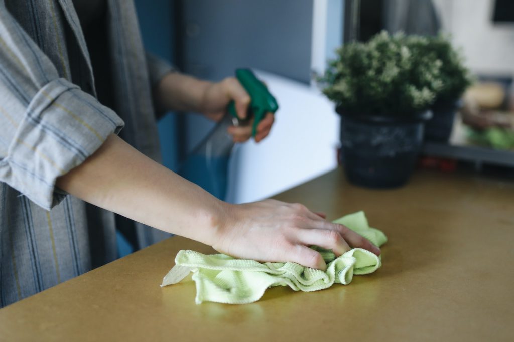 person-wiping-counter-with-cleaning-cloth